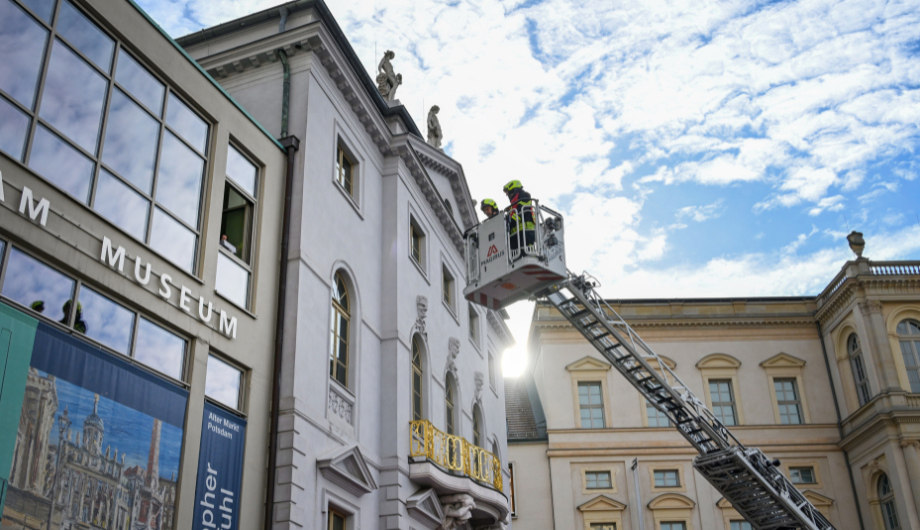 Feuerwehrmänner auf dem Weg nach oben mit der Drehleiter, hin zur Fassade des Museums.