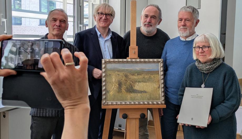 Gruppe steht hinter einem Gemälde