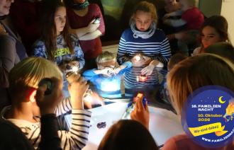Eine Gruppe Kinder mit Taschenlampen im Museum.