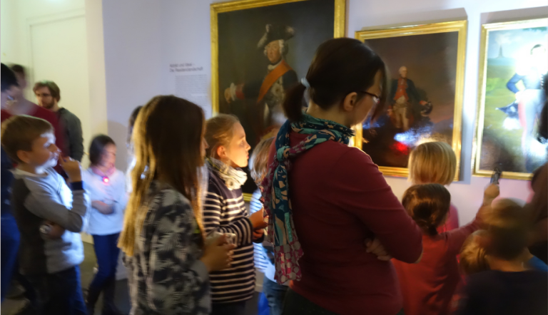 Kinder schauen sich Museumsstücke mit Taschenlampen an.