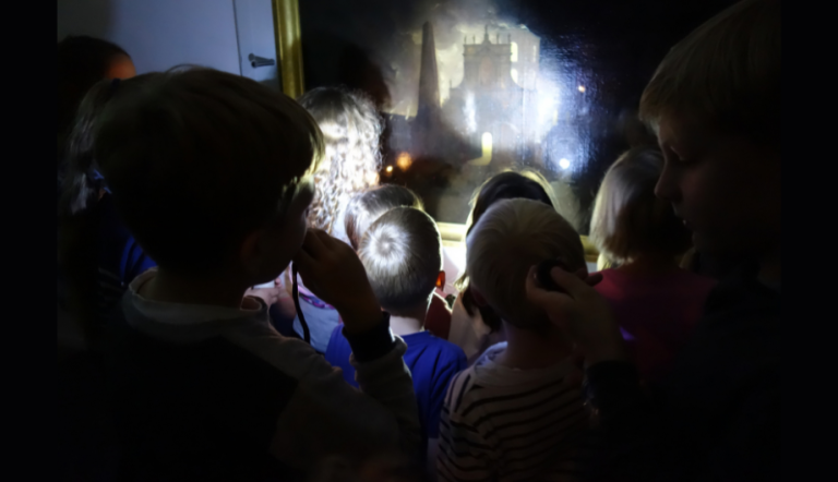Eine Gruppe Kinder mit Taschenlampen im Museum.