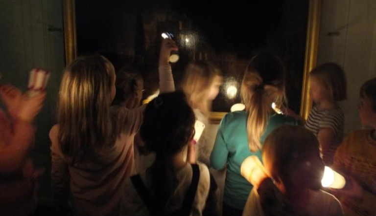 Eine Gruppe Kinder mit Taschenlampen im Museum.